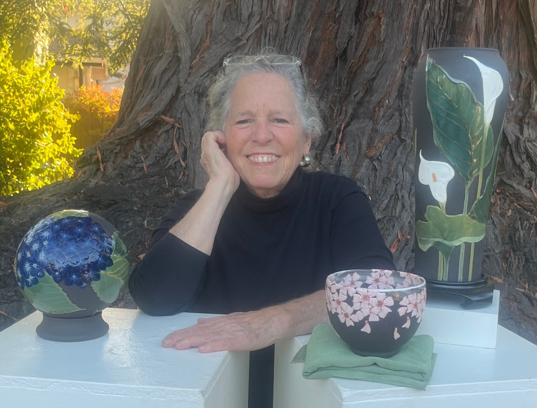Jeannine Calcagno seated outdoors with her stoneware pottery
